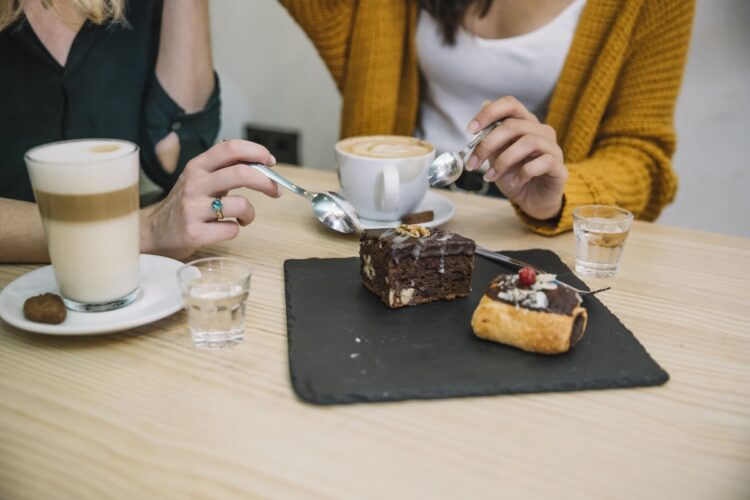 Optimized crop women enjoying dessert drink