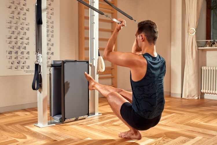 Ascend to Power: Mastering the Art of Upper Body Strength with Calisthenics 54 fit man doing lunge stretch yoga pilates exercise strengthen tone his muscles using reformer gym