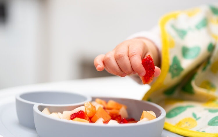 A Taste of Growing Up: Tips for Introducing Solid Foods to Your Baby 53 macro close up baby hand with piece fruits sitting child s chair kid eating healthy food