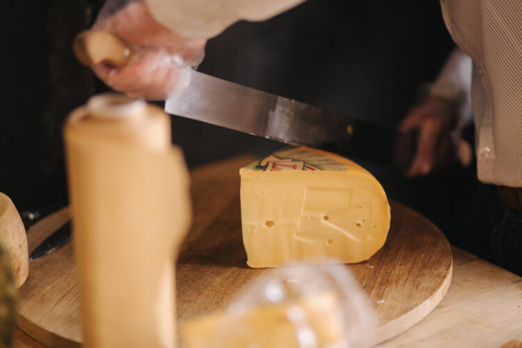 The Art of Cheese Sculpting: A Guide to Creating Edible Masterpieces 51 man slicing cheese wooden board cheese shop