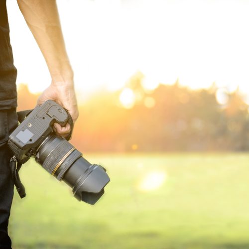 photographer holding camera his hand sunset background